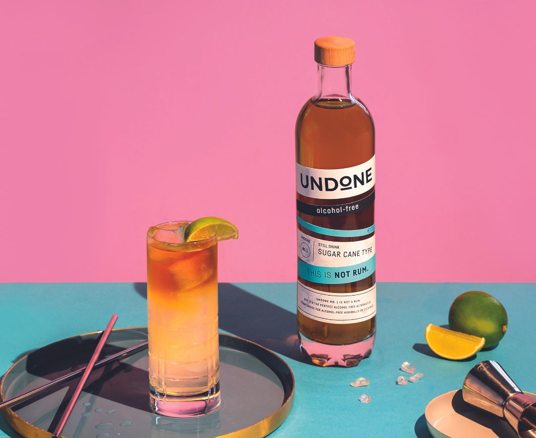 Undone not Rum Flasche mit Rum Drink vor pink-blauen Hintergrund