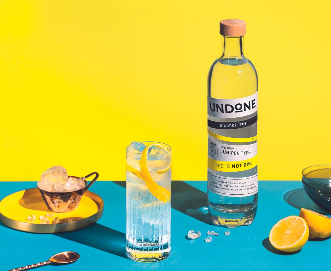 Undone not Gin Flasche mit Gin & Tonic vor blau-gelben Hintergrund