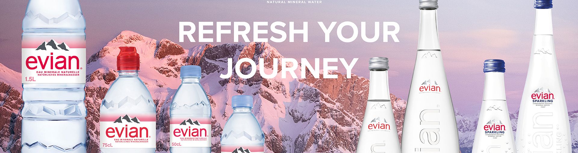 Text "Refresh your journey" mit Evial Plastikflaschen links und Evian Glasflaschen rechts, dahinter ein schneebedeckter Berg im Sonnenuntergang