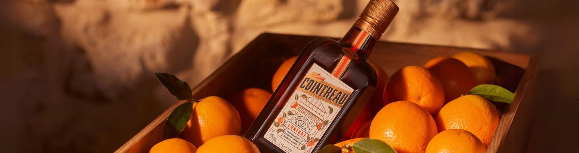 Flasche Cointreau in einer Holzkiste mit Orangen