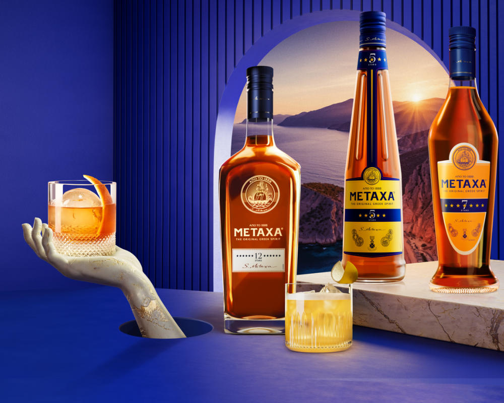 Metaxa Flaschen vor einer blauen Wand mit Fenster mit Blick auf die untergehende Sonne.