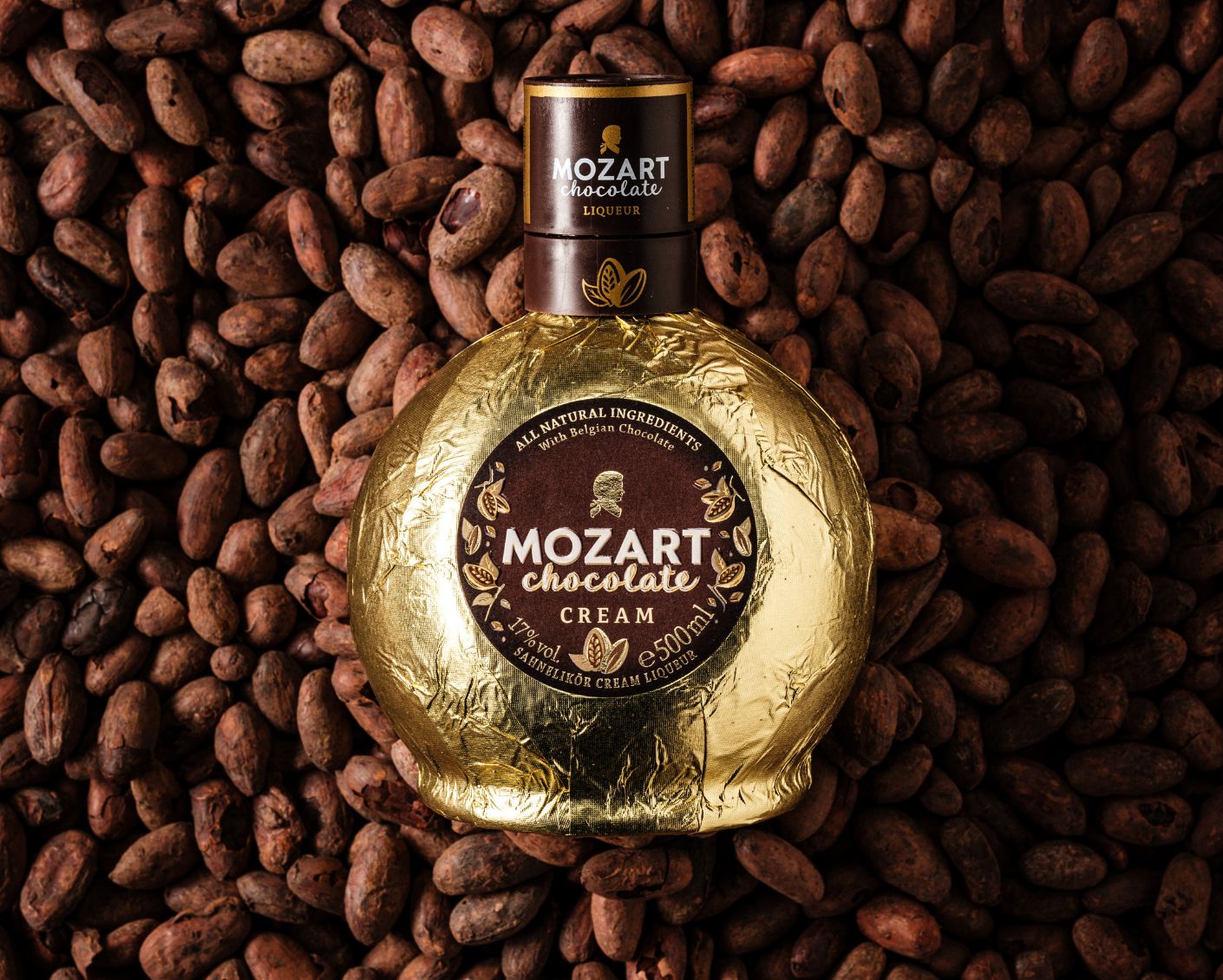 Mozart Chocolate Liqueur Flasche liegt auf Kakaobohnen