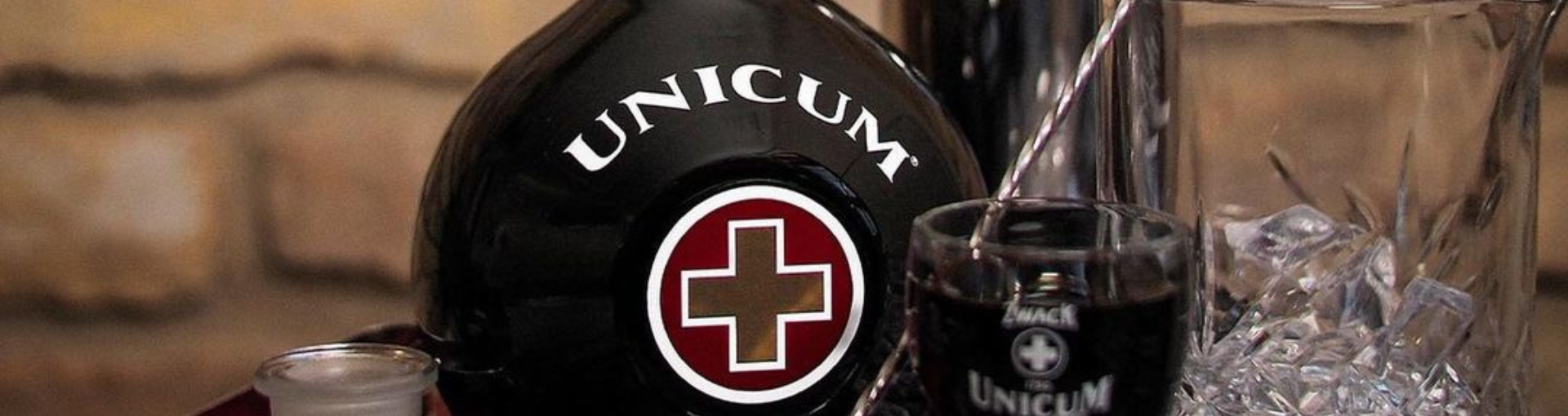 Eine Flasche Zwack Unicum mit einem Shotglas, einem Cocktailglas, einem Rührlöffel und einem Cocktailshaker auf einem Tablett